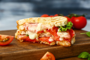 Tasty sandwich with cheese, meat and tomatoes on table