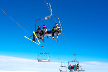 Skiers on chairlift at mountain ski resort with beautiful sky in the background
