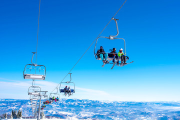 Skiers on chairlift at mountain ski resort with beautiful winter landscape in the background