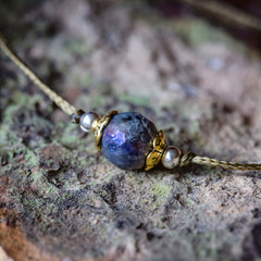 Labradorite fazeted gemstone tiny bracelet on rocky background