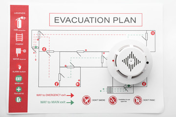 Evacuation plan and smoke detector on white background