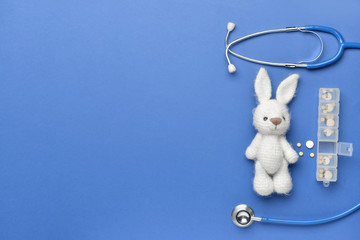 Fototapeta premium Stethoscope, pills and baby toy on color background