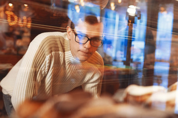 Handsome man choosing sweets and cakes in cafe. Attractive man buying desserts at the coffee shop....