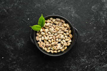 Salted pistachios on a black stone background. free space for your text. Top view.