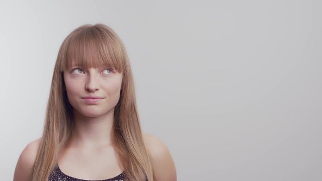Medium shot of a woman eye rolling on a white background in slow motion.