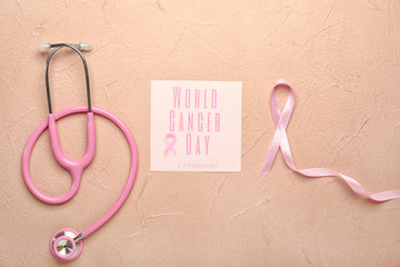 Pink ribbon, stethoscope and paper sheet with text WORLD CANCER DAY on color background
