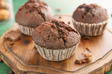Tasty chocolate muffins on wooden board