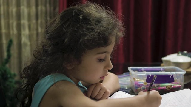 Little girl drawing a picture with color pencil and notebook paper