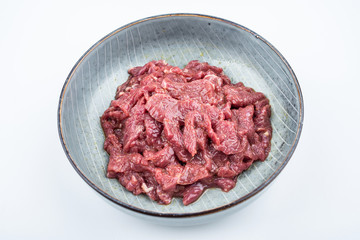 Fresh marinated beef slices on a plate on white background