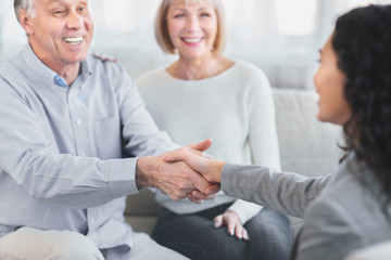 Happy senior couple giving female doctor handshake