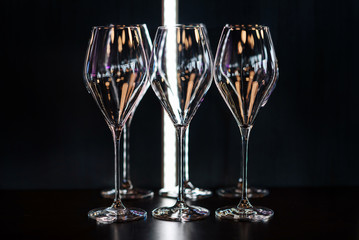 Desert wine glasses on the bar counter. Reflected in glass, neon lights.