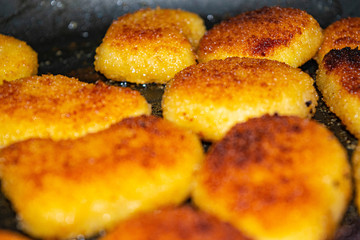 Chicken nuggets are fried in a pan. Close up.