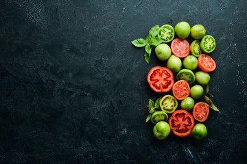 Vegetables. Fresh colored tomatoes On a black stone background. Top view. Free space for your text.