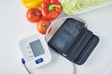 Digital blood pressure monitor and fresh vegetables on the table. Healthcare concept