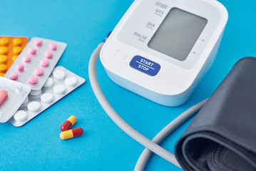 Digital blood pressure monitor and medical pills on a blue background. Healthcare and medicine...