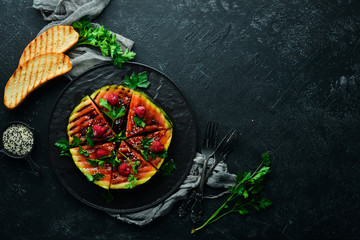 Grilled watermelon with raspberries and parsley on a black plate. Top view. Free copy space.