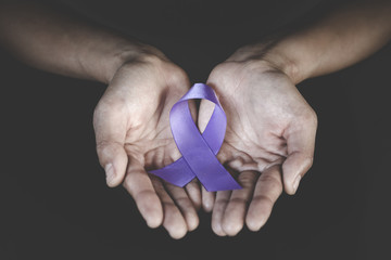 Woman Hand Holding Purple Ribbon, Domestic Violence Awareness Month (October) concept with deep...