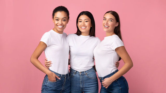 Three Women Embracing Standing In Studio On Pink Background, Panorama