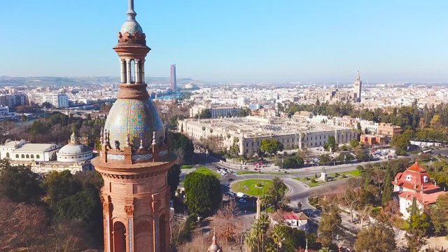 Generic cinematic aerial view of beautiful Spanish Square in centre of Seville. Close-up of tower. In background beautiful University of Seville, Cathedral of Seville and river Guadalquivir. Forward