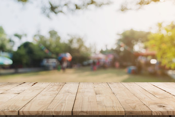 Empty wood table and defocused bokeh and blur background of garden trees in sunlight, display montage for product.