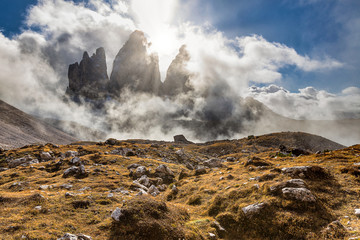 Tre Cime di Lavaredo famous rocky mountains view with sun shining through the clouds
