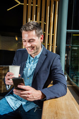 smiling businessman sitting at cafe looking at cellphone