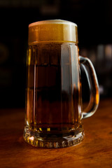 Beer in a Mug with Foam Resting on a Wooden Surface