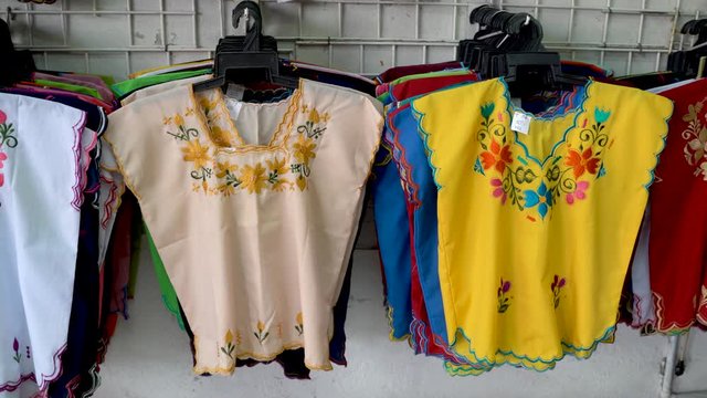 Camera moving to right and panning left showing colorful designer huipil blouses indigenous to Merida, Yucatan, Mexico.