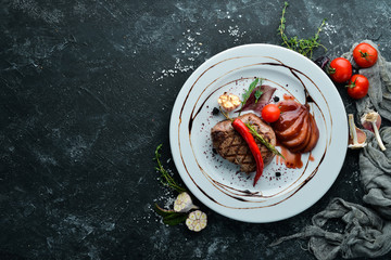 Juicy veal steak with chili pepper and pear on a plate. Top view. Free copy space.