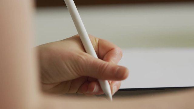 Womans hand drawing on an iPad whilst using a stylus