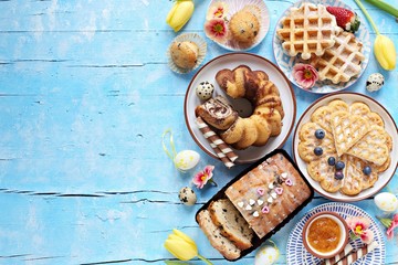 Easter festive dessert table with various of cakes, waffles, sweets and strawberry. Blue background. Overhead view
