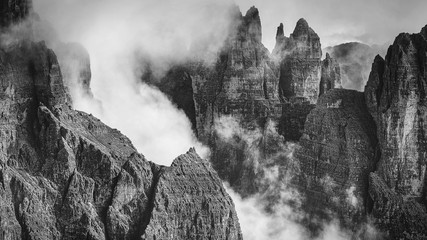 Black and white rocky mountains view covered with clouds, Dolomites, Italy