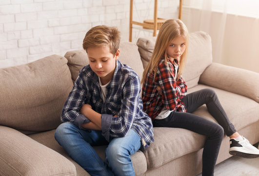 Siblings After Quarrel Sitting Back-To-Back On Couch At Home