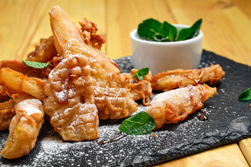 Close up view of deep fried fruits in breading served with caramel and strawberry jam
