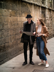 Beautiful and style friends walking with map and camera through the street.