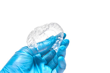 Hand is holding set of custom dental trays for bleaching teeth. Isolated on a white background