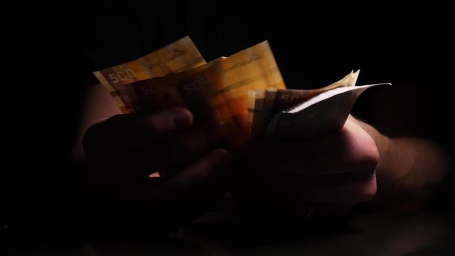 A man counts out Norwegian Krone and drops them on a table - concept: bribe, corruption, pay off, illegal