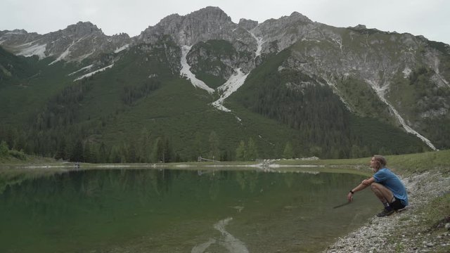 Mountain by a lake with runner resting by the lake, with cloudy weather, beautifull view in the alps in austria innsbruck 4k