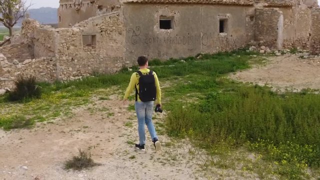 slow motion cinematic shot of young millennial man exploring old ruins with his camera