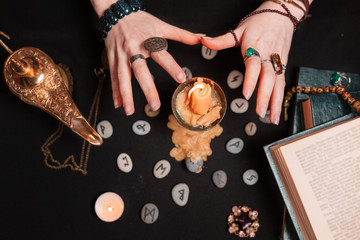 Astrology and esotericism. Female witch hands divination over a candle. On a black background lie...