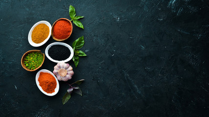 Colorful herbs and spices for cooking. Indian spices. On a black stone background. Top view.