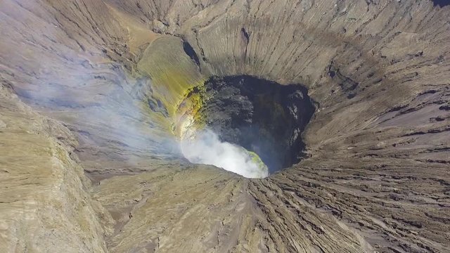 Aerial drone view of active volcanic crater of Mount Bromo with smoke. Bromo Tengger Semeru National Park, East Java, Indonesia.