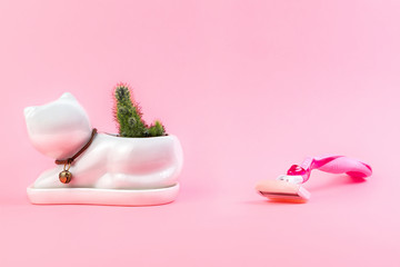Fototapeta na wymiar A cactus in a White flower pot, like a cat, and next to it is a razor on a pink background. The concept of depilation and epilation. Copy space