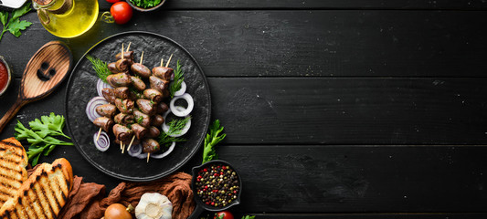 Baked chicken heart on skewers in a black plate. Chicken meat. Top view. Free space for your text.