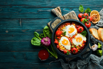 Fried eggs with vegetables: tomatoes, paprika, peppers, onions. Vegetable Shakshuka in a pan. Top...