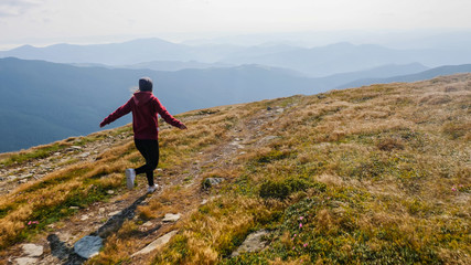Obraz premium Back view of girl running on the mountain valley.