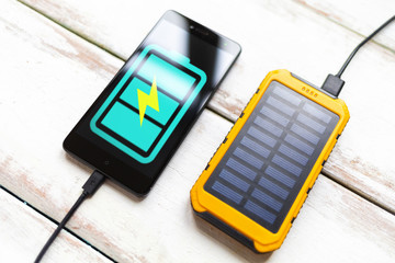 Concept of modern technologies and power bank. Smartphone with a turquoise battery icon, charged...