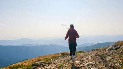 Obraz premium Back view of girl running on the mountain valley.