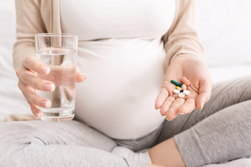 Pregnant woman taking dietary supplements at home