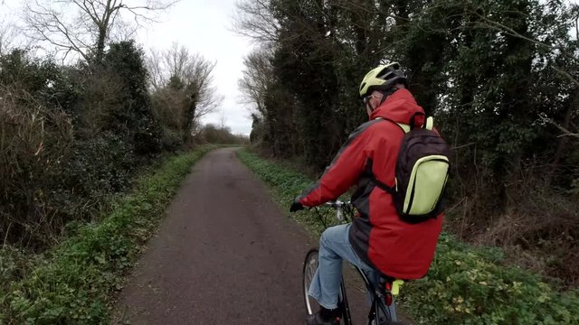 Man with Red Jacket cycling into Frame down country lane, tracking shot